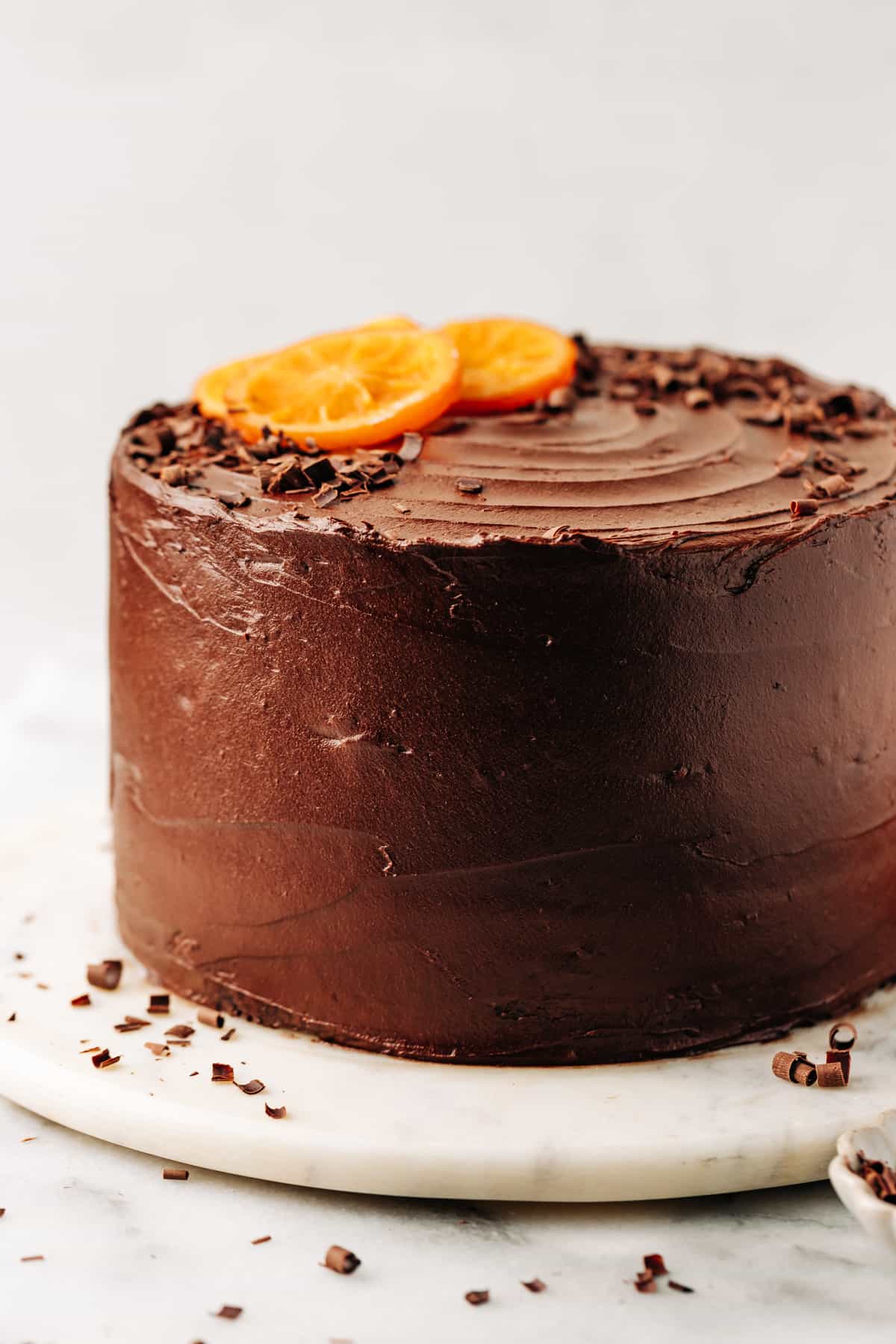 a three layer chocolate orange cake on a cake plate.