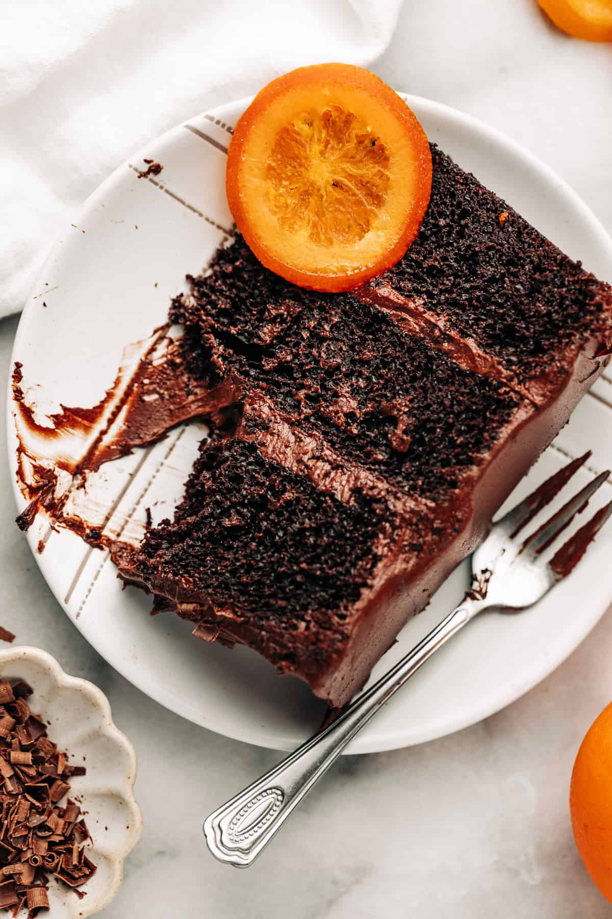 a slice of chocolate orange cake with fudge frosting on a plate.