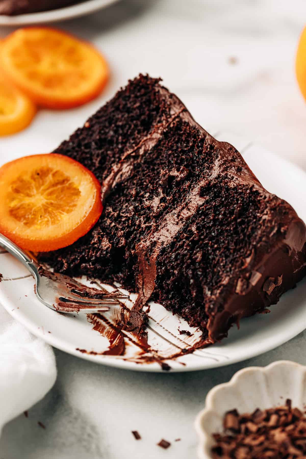 a slice of chocolate orange cake on a plate with a candied orange.