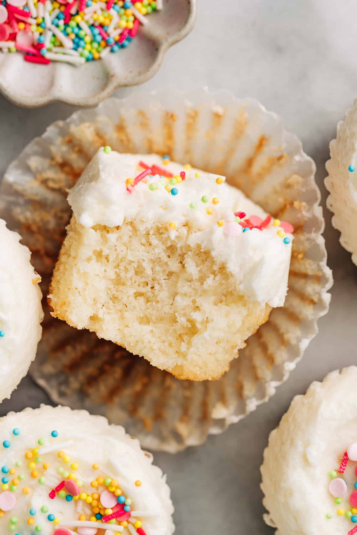 moist and fluffy vanilla cupcake made with oil topped with vanilla buttercream cut in half.