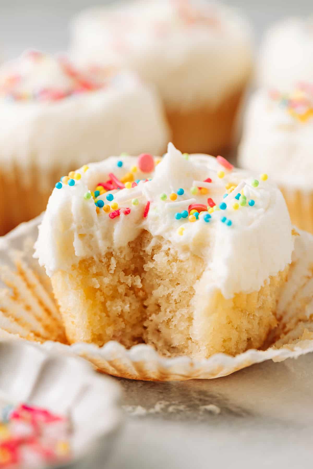 Bite shot of a moist vanilla cupcake with oil topped with vanilla buttercream frosting. 