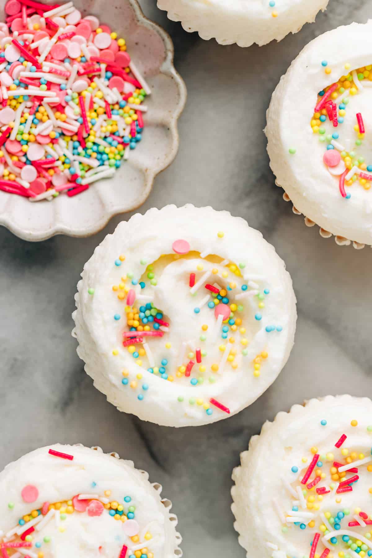 vanilla buttercream on cupcakes topped with sprinkles.