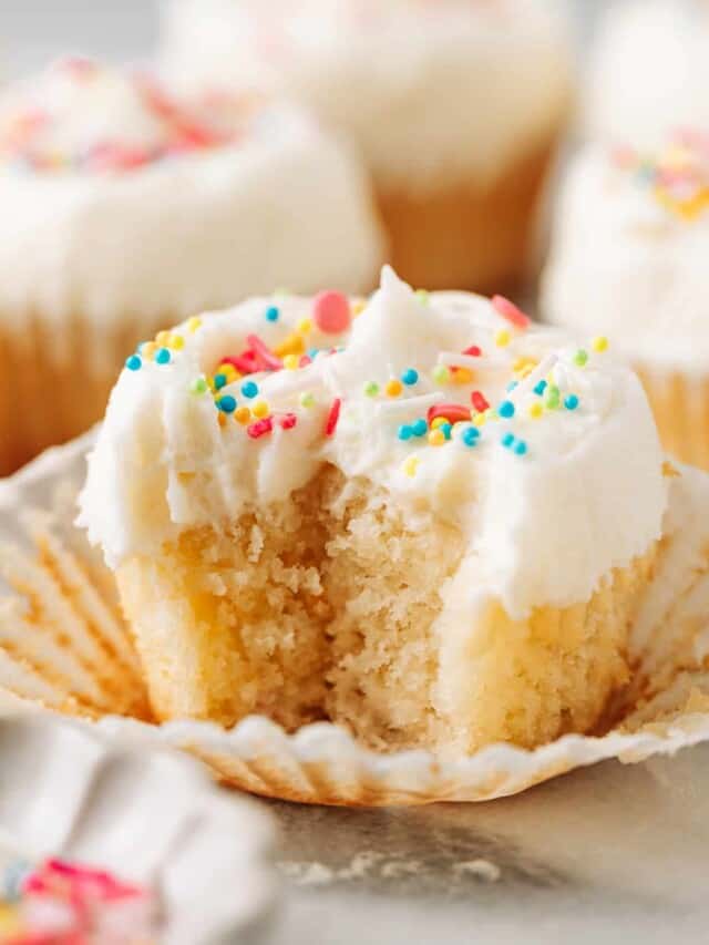 Bite shot of a moist vanilla cupcake with oil topped with vanilla buttercream frosting.
