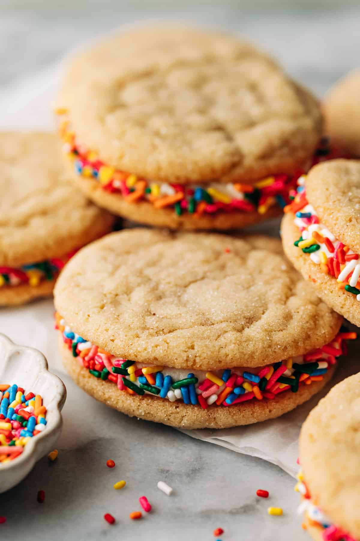 pile of cookie sandwiches with rainbow sprinkles.