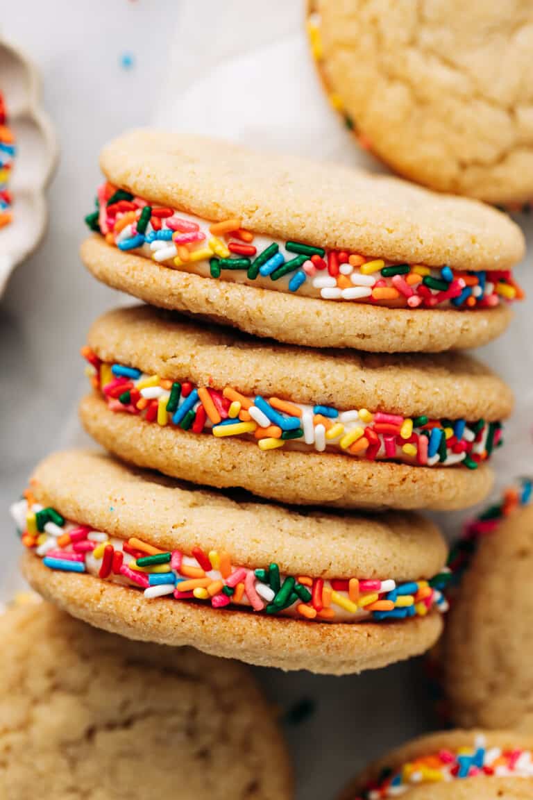 bird's eye view of three sugar cookie sandwiches with buttercream frosting and rainbow sprinkles.