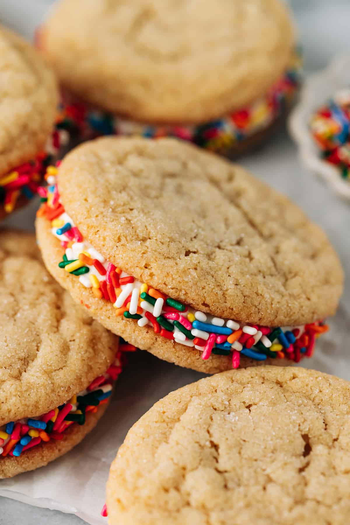 sugar cookie sandwiches with rainbow sprinkles on parchment paper.