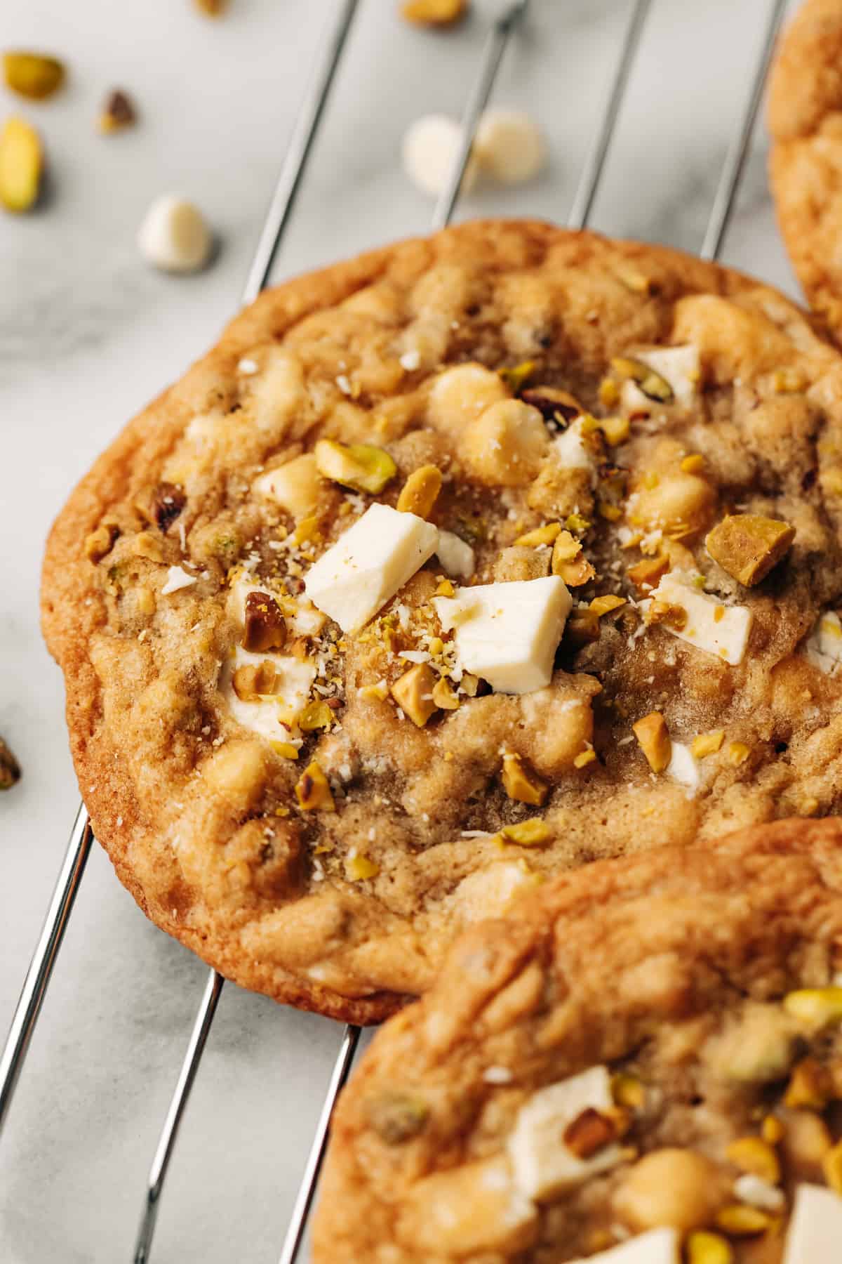 a pistachio white chocolate chunk cookie on a wire rack.