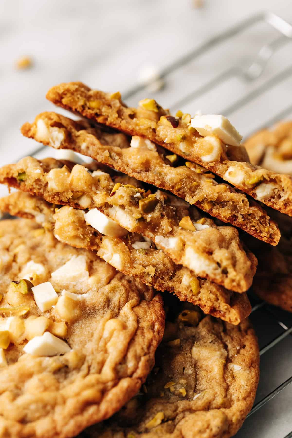 pistachio white chocolate cookies cut in half on a wire rack.